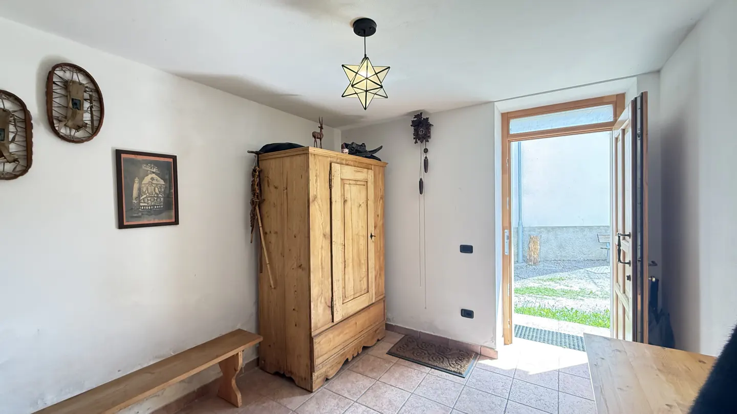 Entryway with a wooden bench, a tall wooden cabinet, and an open door to the outside. A star-shaped light fixture hangs from the ceiling.