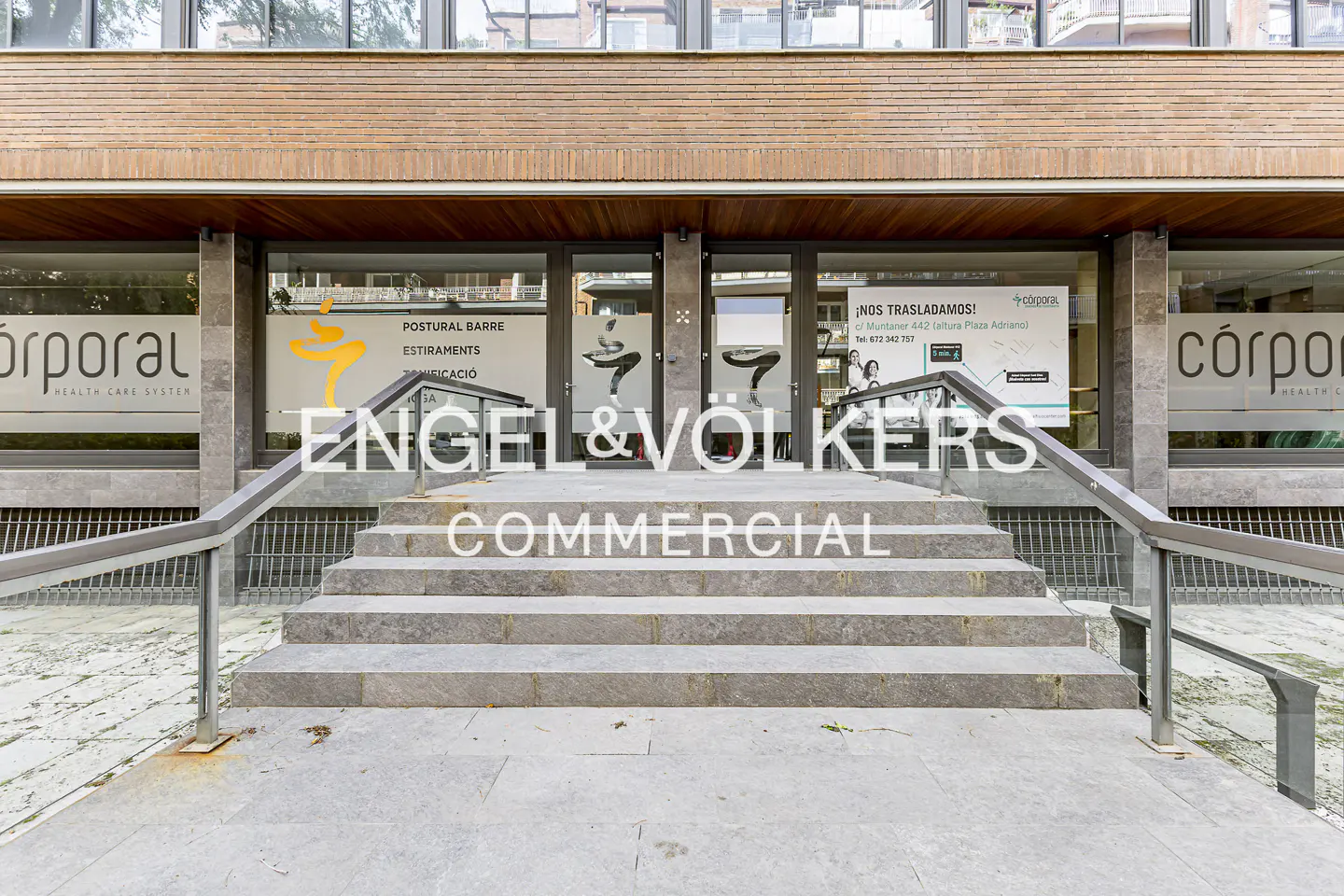 Engel & Völkers Commercial office entrance with stone steps and metal railings. Glass doors and windows with company logos.