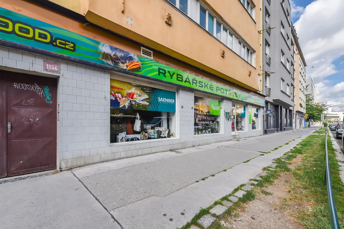 Street view of a fishing supply store with large window displays and a brown door to the left.