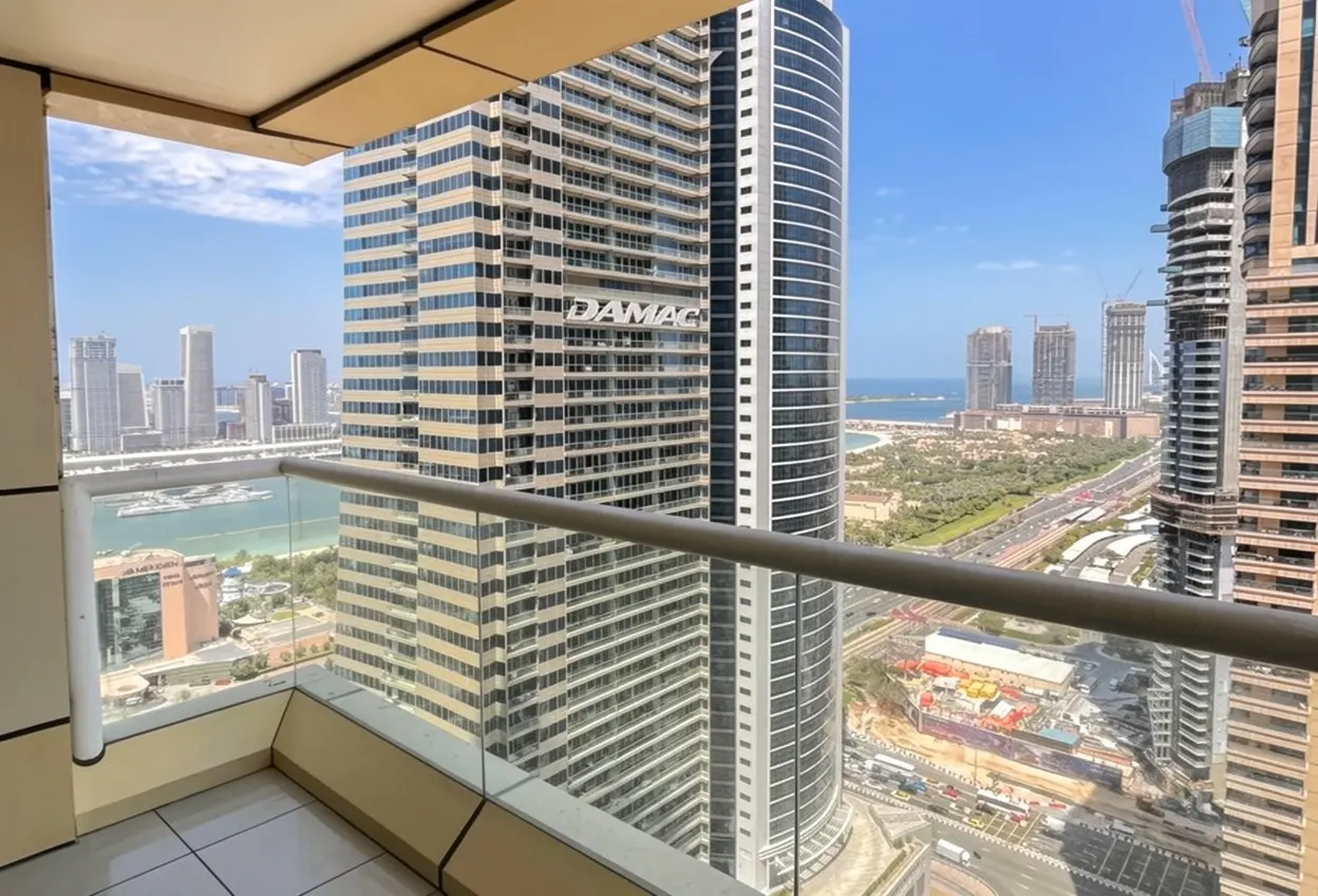View from a high-rise balcony overlooking a modern city skyline with tall skyscrapers, a highway, and the distant coastline.