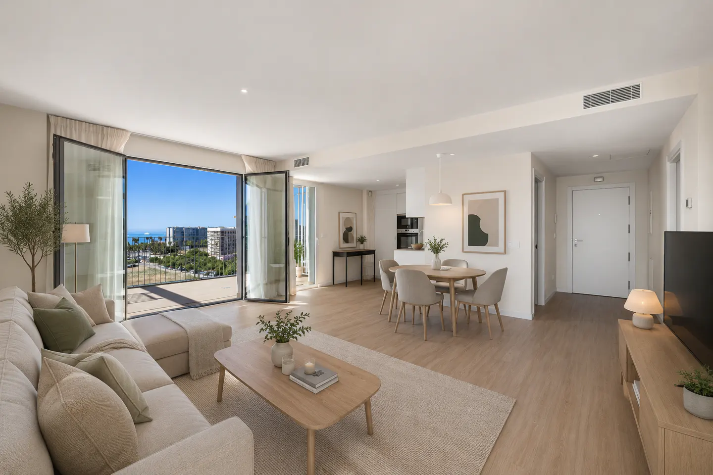 Bright, modern living room with a beige sofa, wood floors, and a view of the city and ocean through open glass doors.