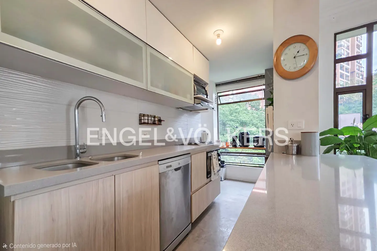 A modern kitchen with light wood cabinets, stainless steel appliances, and a gray countertop. A window overlooks lush greenery. A clock hangs on the wall.