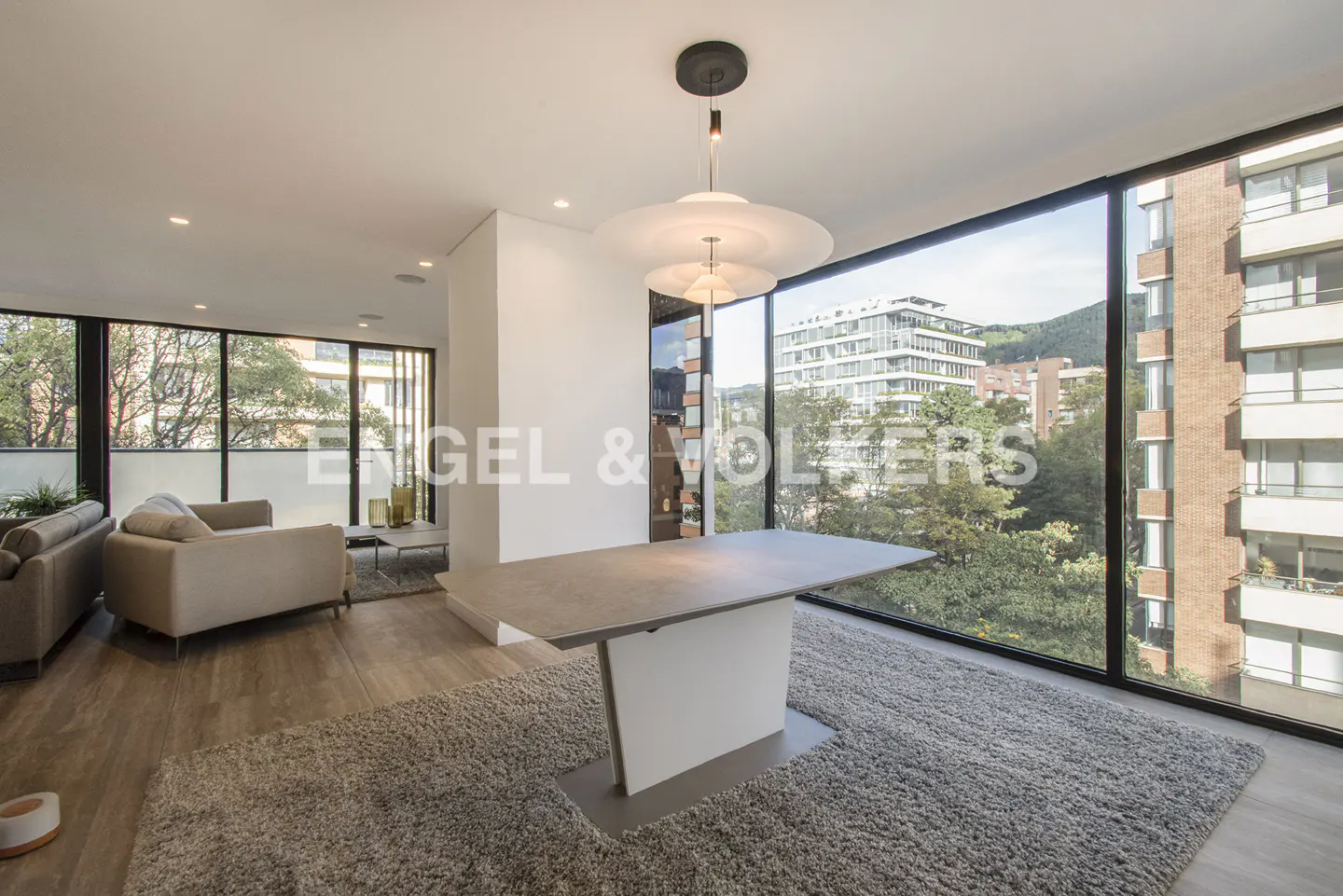 A modern living room with a gray rug, a table, and a large window with a city view.