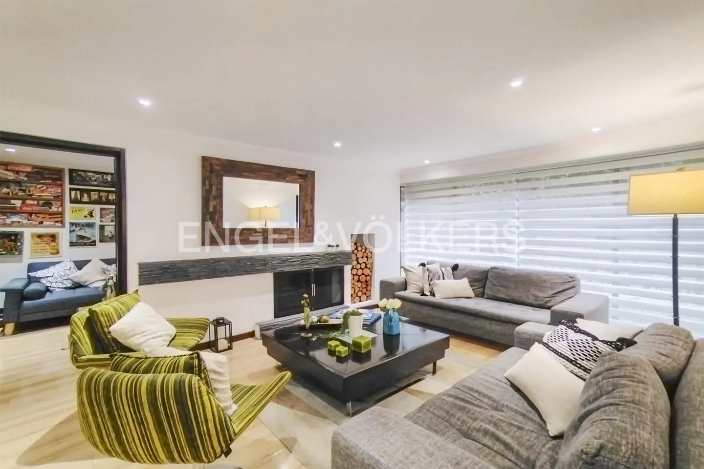 Living room with gray sofas, striped green chairs, and a black coffee table. A fireplace with a wood-framed mirror is on the wall.