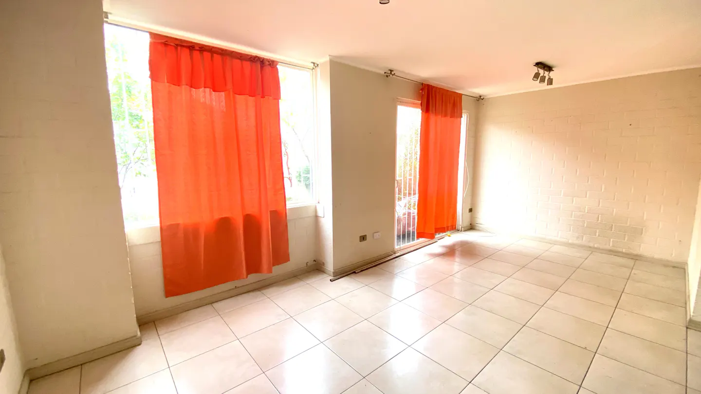Bright, empty room with white tile floor, white walls, and orange curtains on two windows.