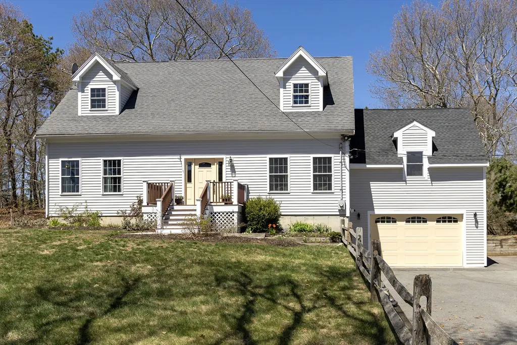 Exterior of a two-story house with light gray siding, a gray roof, and a yellow front door. A garage is attached to the right side.