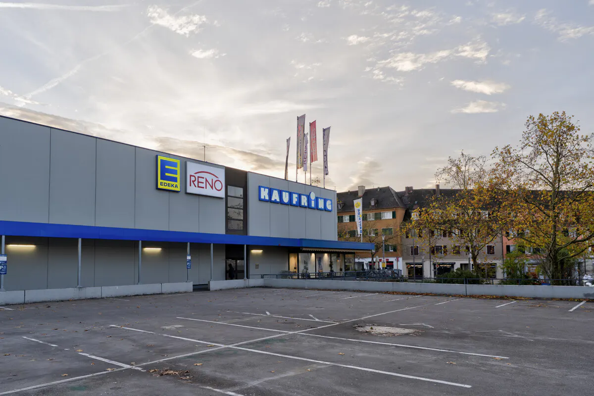 Exterior view of a Kaufring store with Edeka and Reno logos, featuring an empty parking lot and nearby buildings.