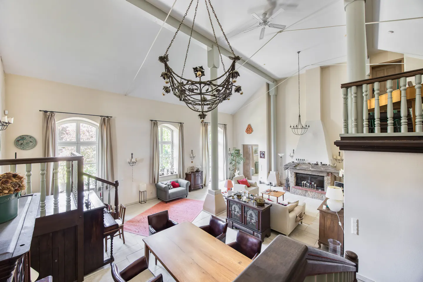 A high-angle view of a spacious living room with a vaulted ceiling, large windows, and a decorative chandelier.