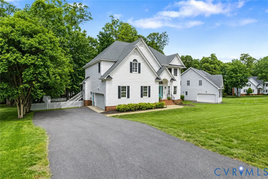 Two-story white house with black shutters, a gray roof, and a turquoise front door. A long driveway leads to the house.