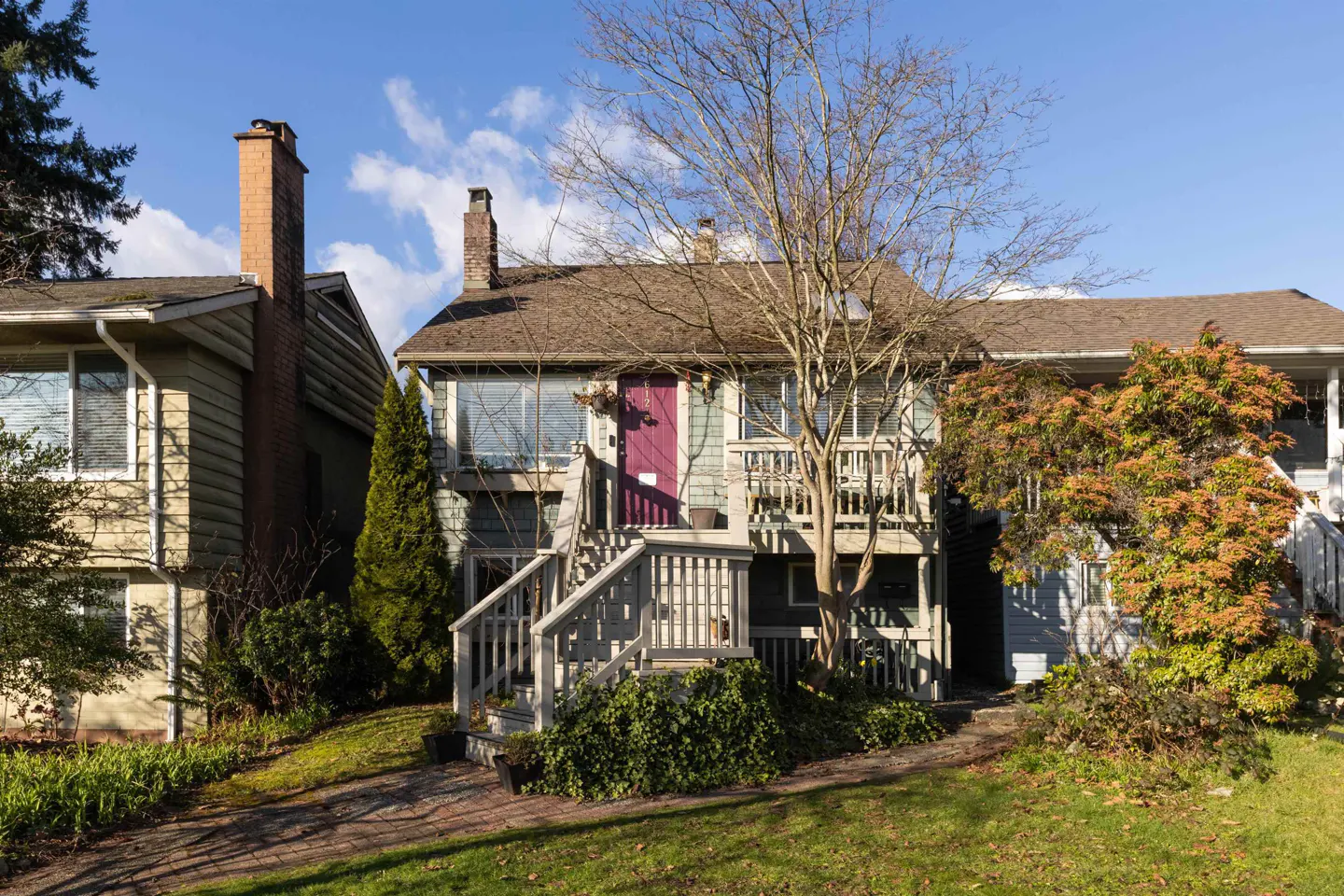 Two-story house with a purple door and gray stairs leading to the entrance. A bare tree stands in front of the house.