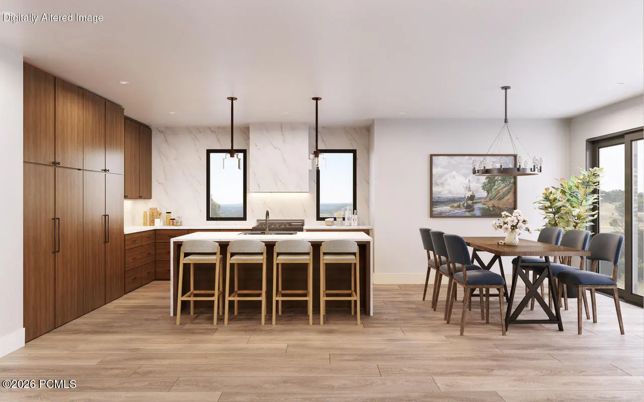 A modern kitchen and dining area with wood floors, cabinets, and a white island with stools. A dining table with blue chairs sits near a sliding glass door.
