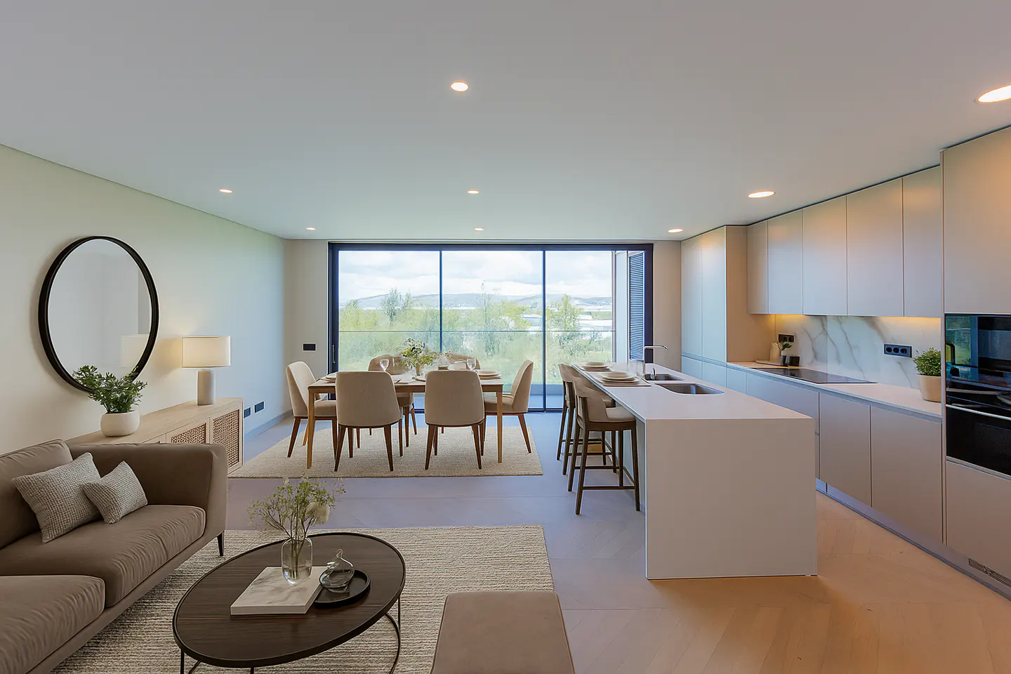 Open-concept living space with a taupe sofa, dining table, and white kitchen island. Large windows overlook a green landscape.