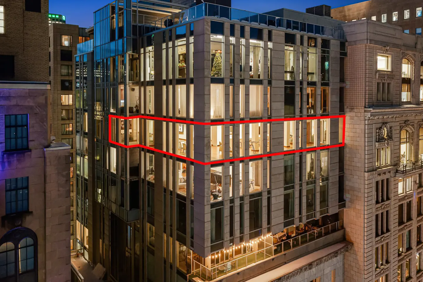 Exterior view of a modern high-rise building with a red rectangle highlighting a floor with large windows.