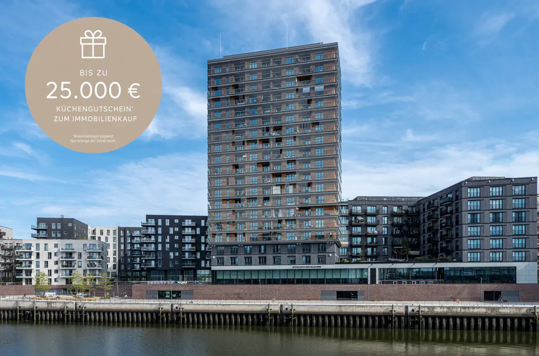 Modern apartment buildings by a river, under a blue sky. A beige circle offers a kitchen voucher for real estate purchase.