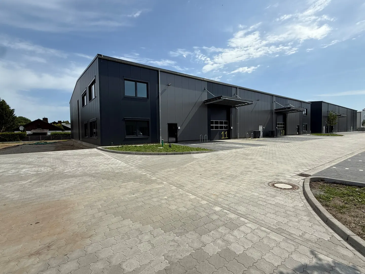 A long, gray, one-story warehouse building with loading docks and a paved parking lot.