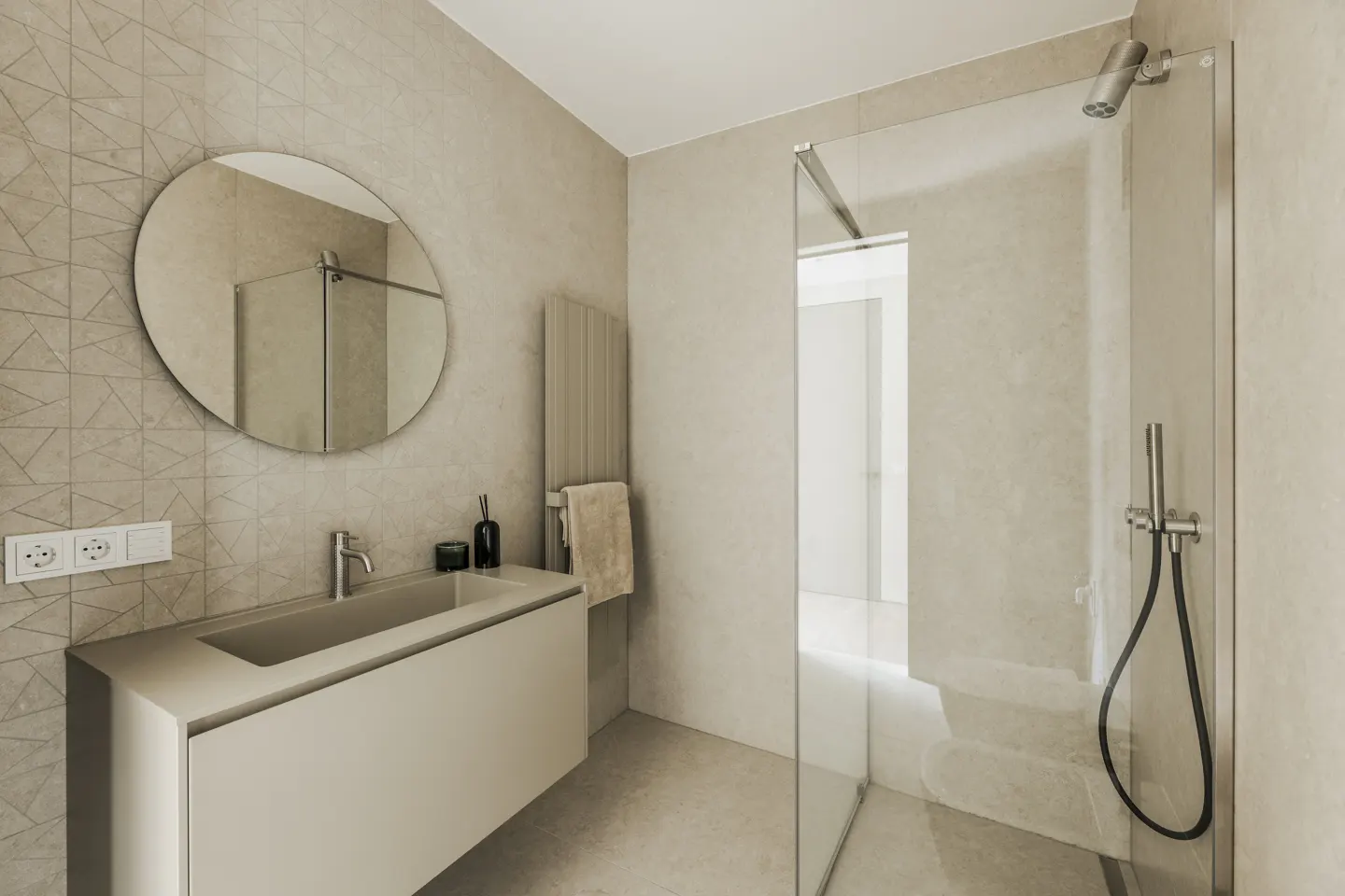 Modern bathroom with beige walls, a round mirror above a floating sink, and a glass-enclosed shower.