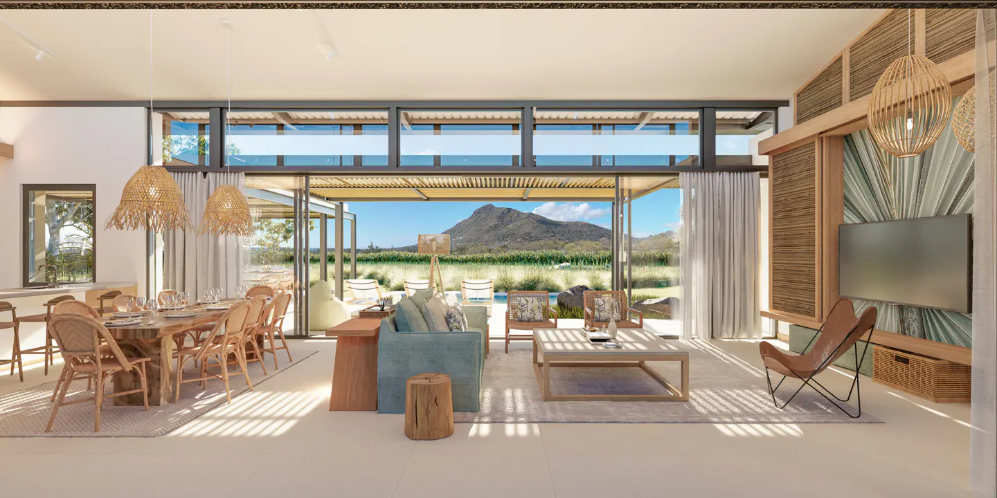 Bright, open living space with dining table, rattan chairs, and mountain view through glass doors. Wicker light fixtures hang above.