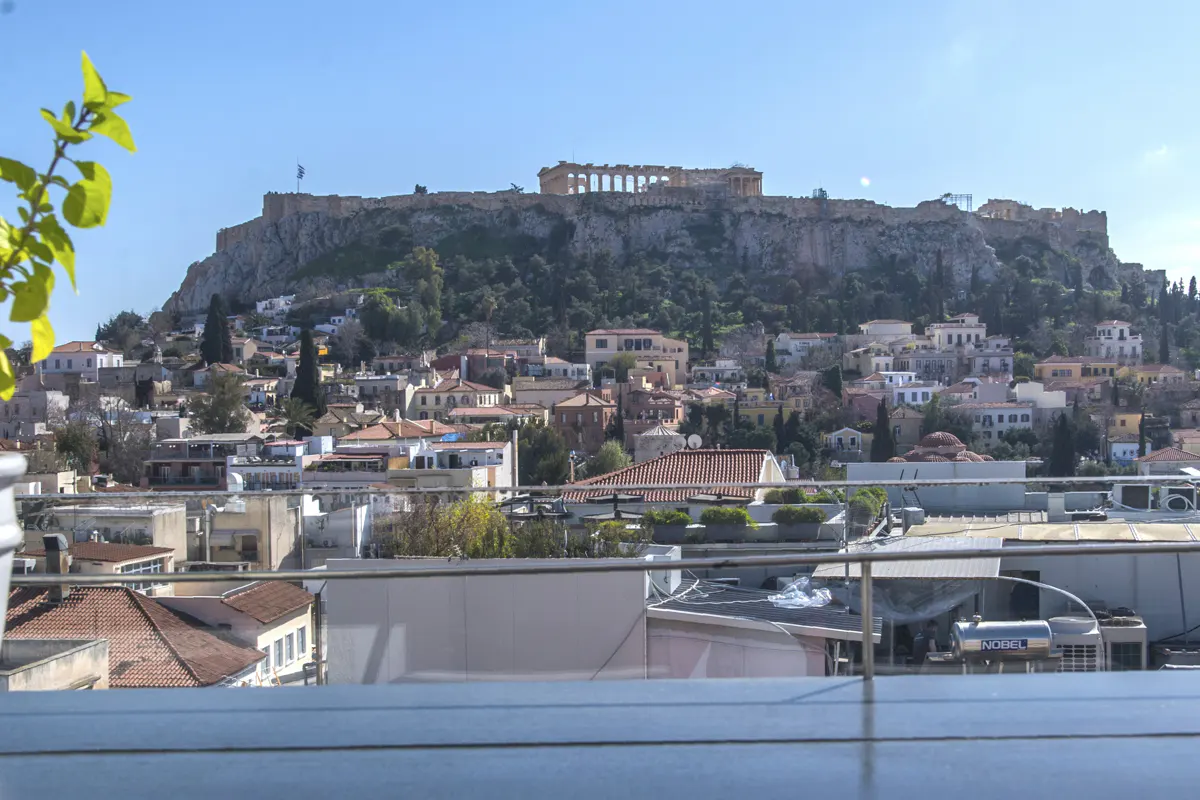 Athens cityscape view with the Acropolis on a hill, seen from a rooftop on a sunny day.