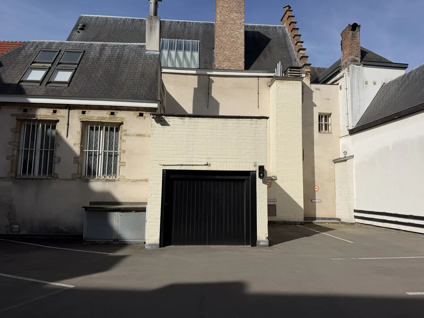 Exterior view of a building with a black garage door and a green traffic light.