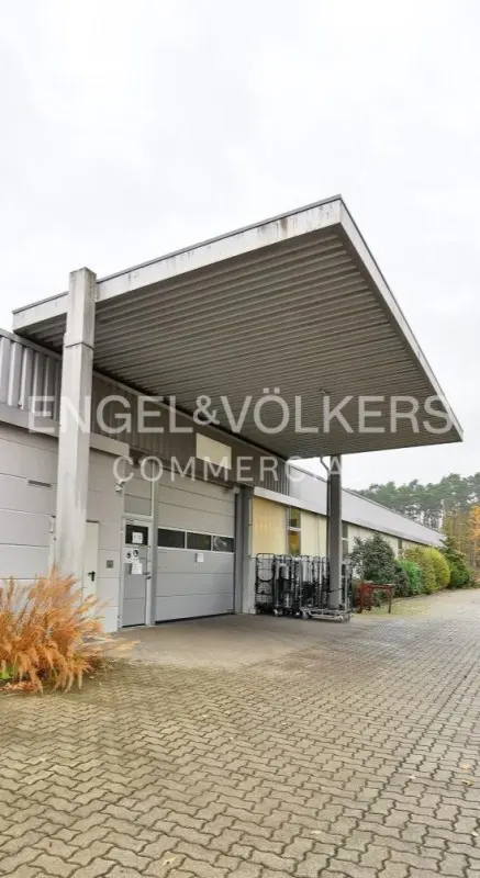 Engel & Völkers commercial building with a gray awning, loading dock, and a brick-paved parking lot.