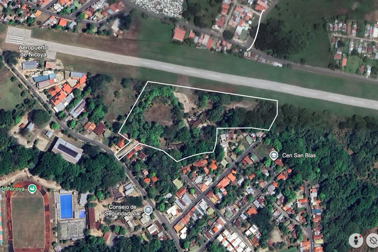 Aerial view of a property outlined in white, near Nicoya Airport, surrounded by trees and houses.