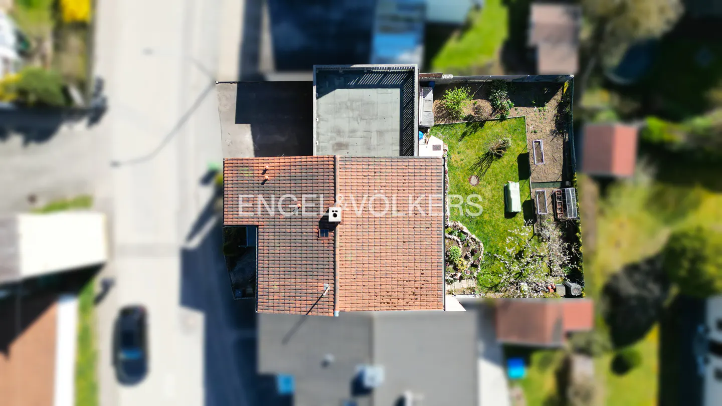 Aerial view of a house with a red tile roof, a green lawn, and the Engel & Völkers logo.