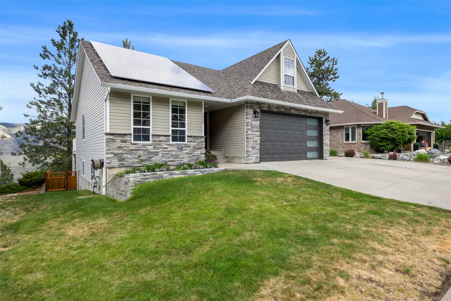 A two-story house with a gray roof, gray siding, and a gray garage door, with a green lawn in front.