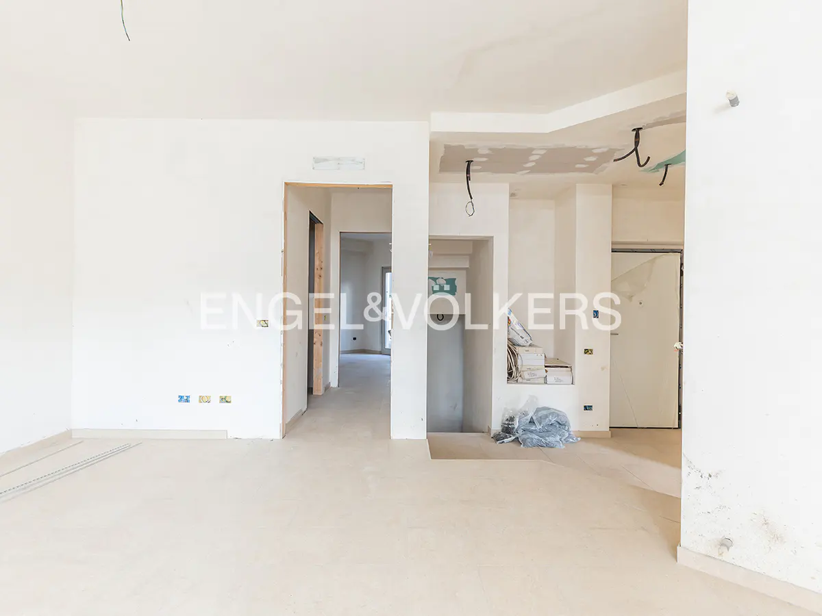 Unfinished white room with doorways, exposed wiring, and construction materials. Engel & Volkers logo is visible.