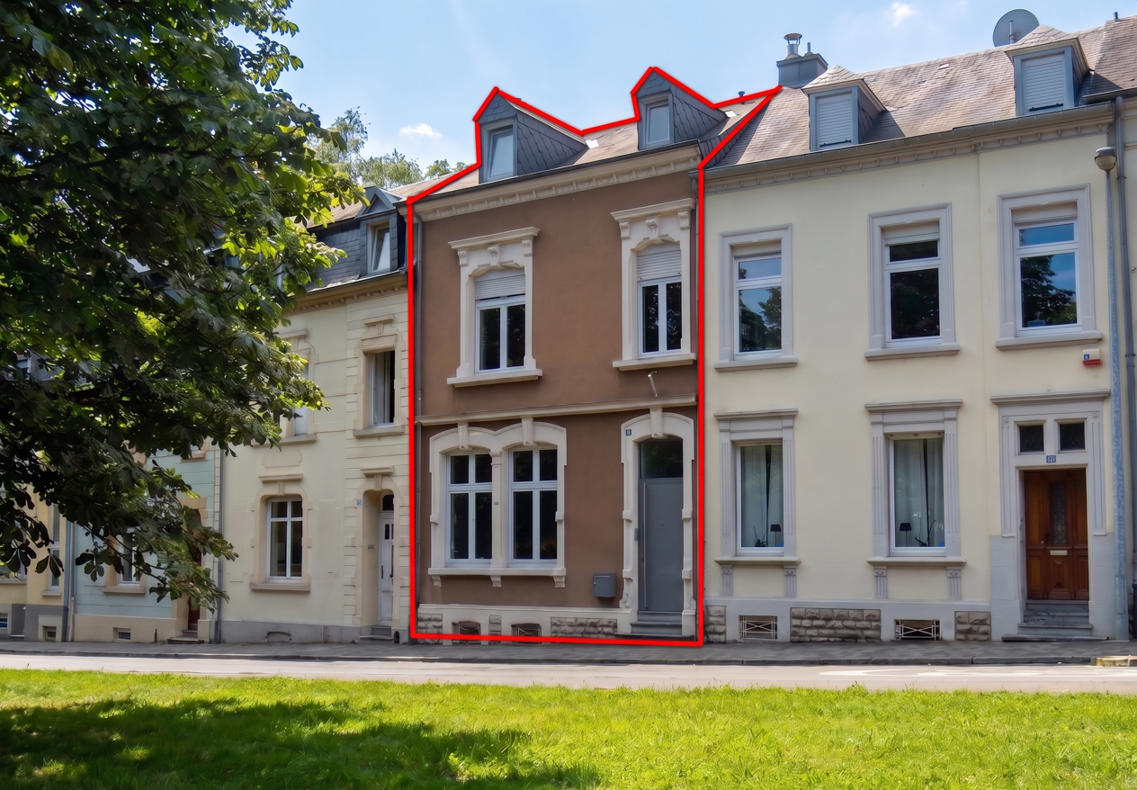 A brown three-story townhouse outlined in red, situated in a row of similar homes along a street with a grassy foreground. [AI-generated text]
