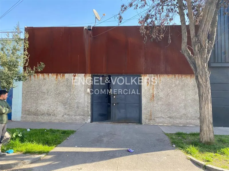 Commercial building with a rusty metal top, concrete base, and blue doors. Engel & Volkers logo is visible.
