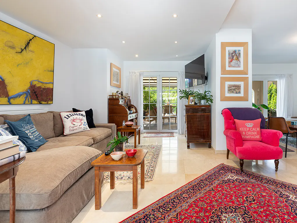 Bright living room with a brown sectional sofa, red armchair, and a large yellow abstract painting on the wall.