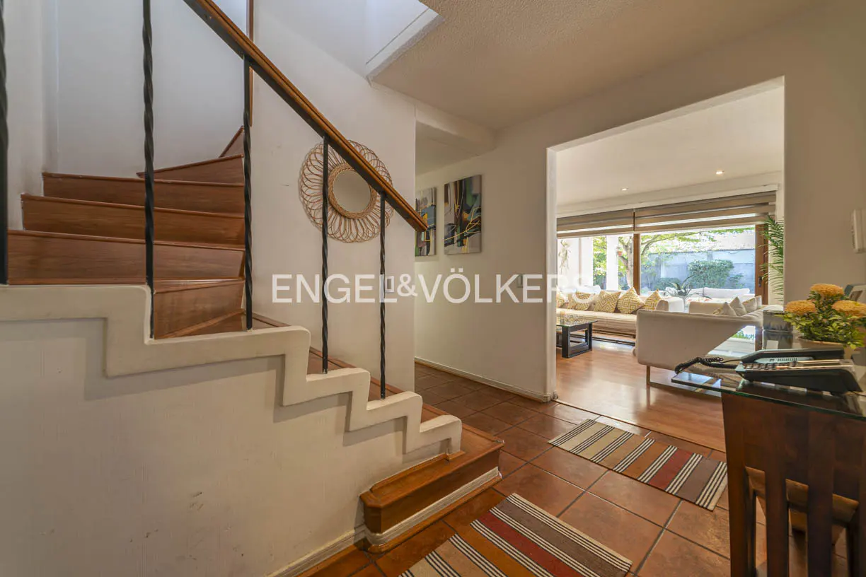 Interior view of a home featuring a staircase with wooden steps and a black railing, leading to a living room with a sofa.
