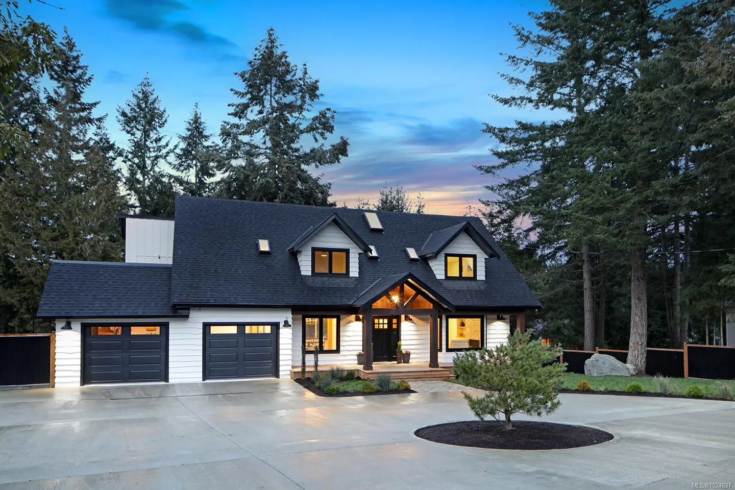Two-story white house with black trim, a black roof, and a two-car garage, surrounded by tall trees.