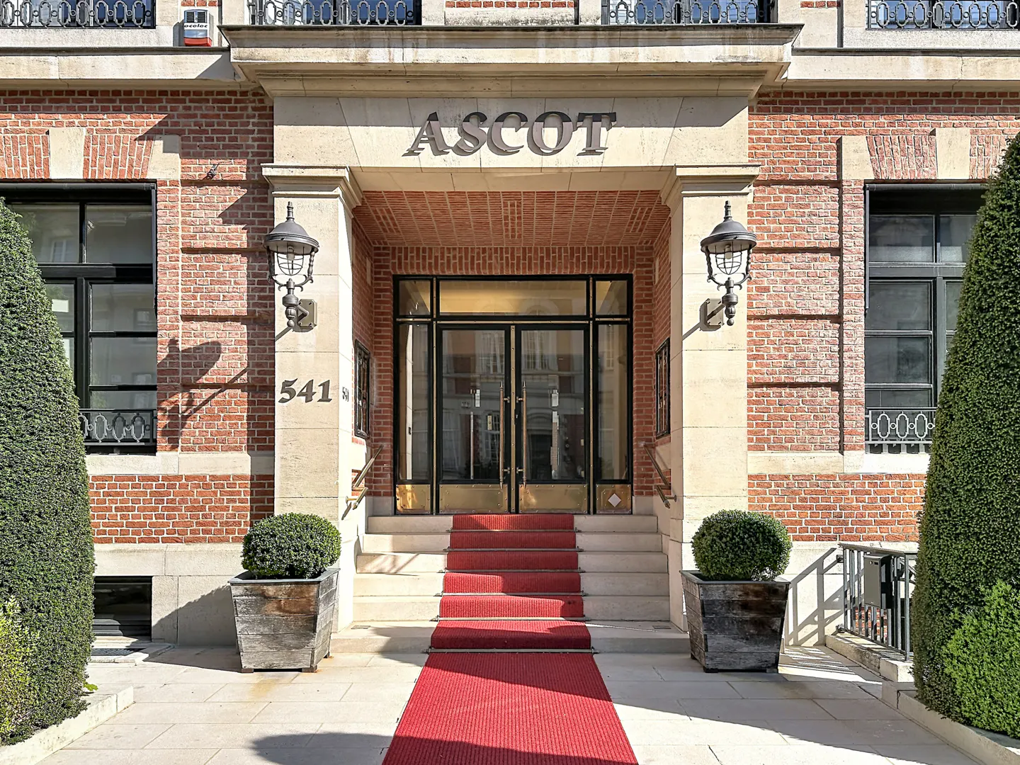 Exterior of the Ascot building with a red carpet leading to the entrance doors. Address number 541 is visible.