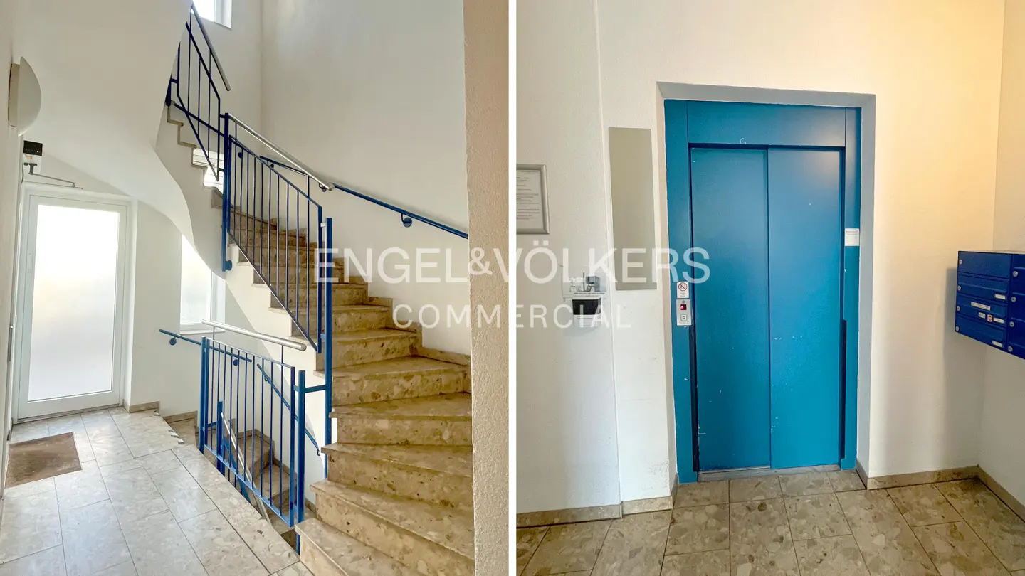 Interior shot of a building lobby with stairs and a blue elevator. The stairs have blue railings and marble steps. Mailboxes are visible next to the elevator.