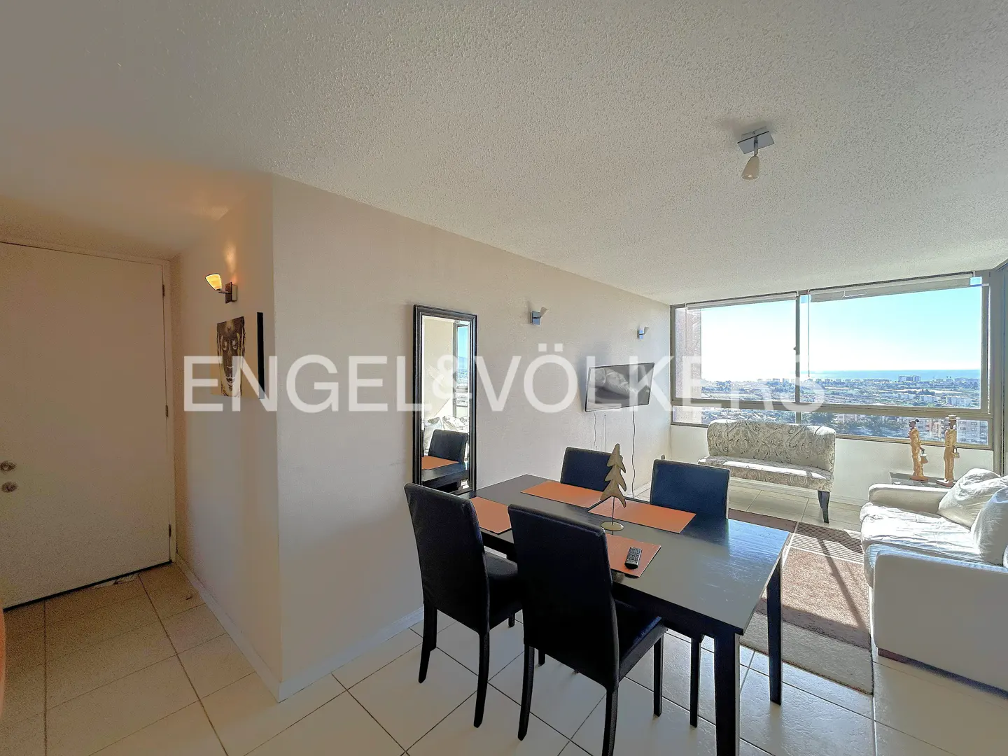 Apartment interior with a black dining table, chairs, and a view of the city through large windows.