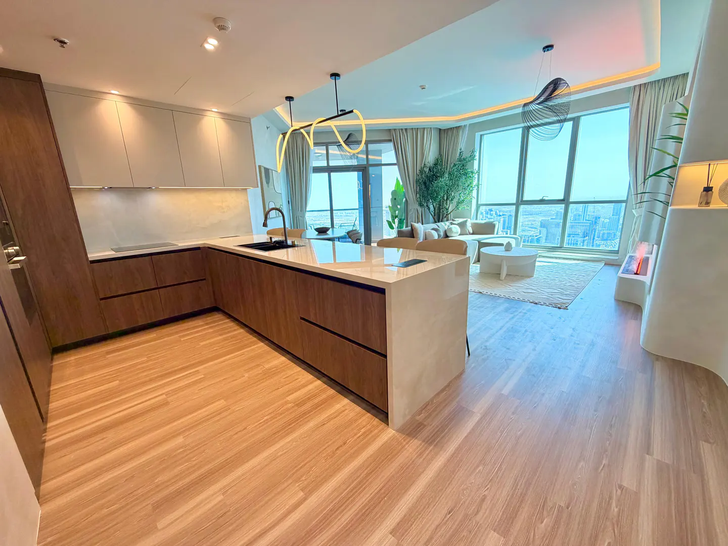 Open-concept apartment with wood floors, a kitchen island, and a living area with a large window overlooking a city.