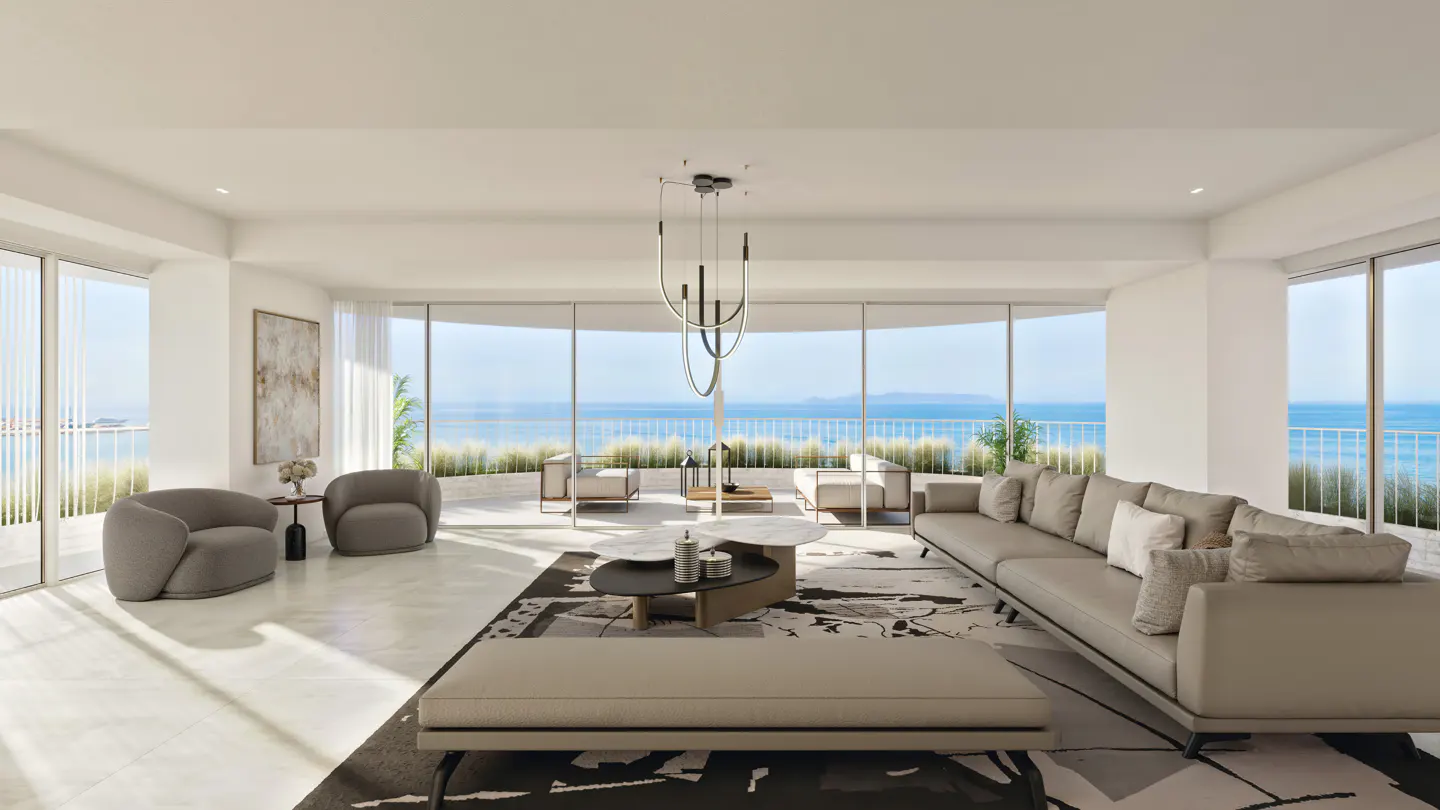 Bright, modern living room with ocean view. Gray sofa, chairs, and patterned rug. Large windows overlook the sea.