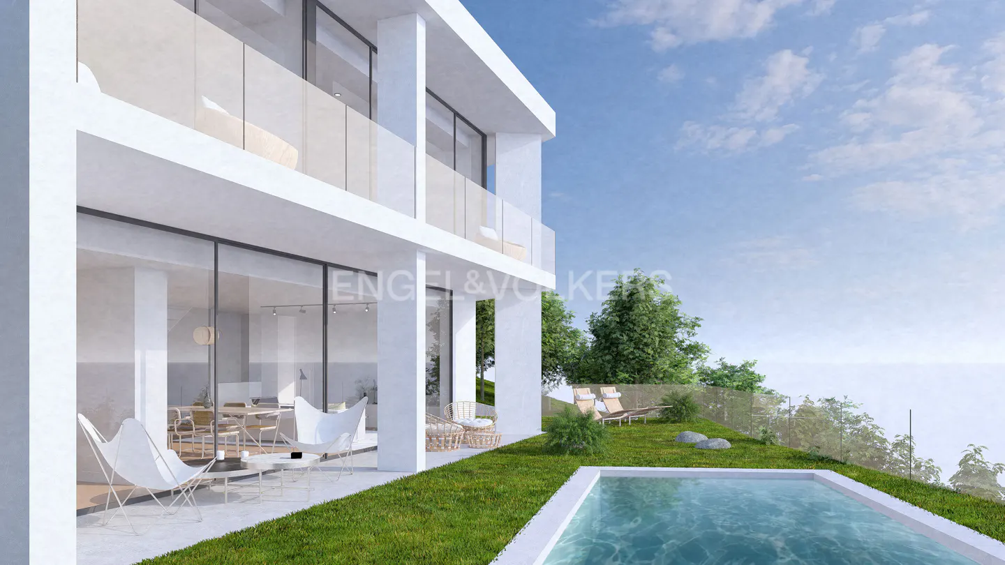 Modern white two-story house with a pool, lawn, and patio furniture on a sunny day. Engel & Volkers logo visible.