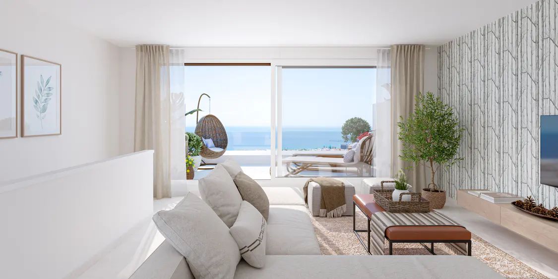 Bright living room with white sofa, pillows, and a view of the ocean through a sliding glass door. A hanging chair sits on the balcony.