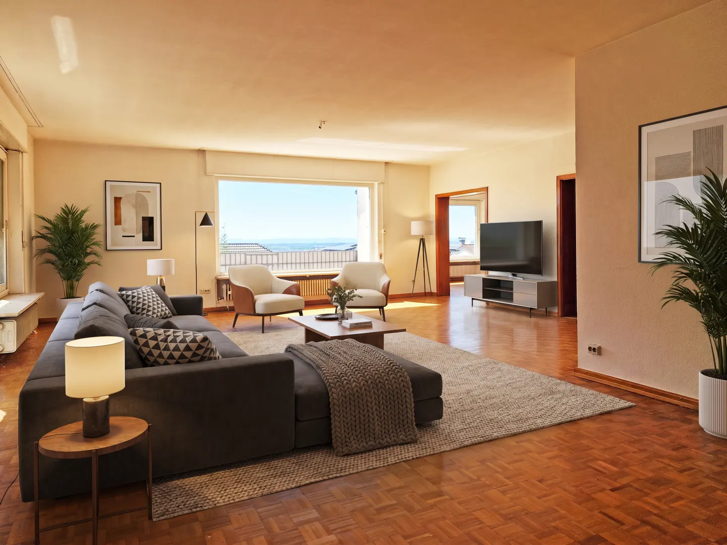 A spacious living room with a gray sectional sofa, two armchairs, and a large window with a sea view.