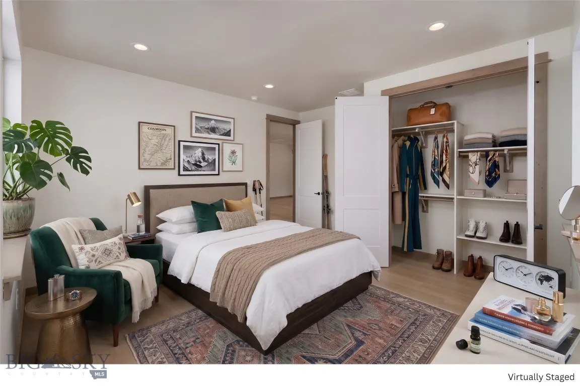 Bedroom with white walls, a bed with white linens, a green chair, and an open closet with clothes and shoes.