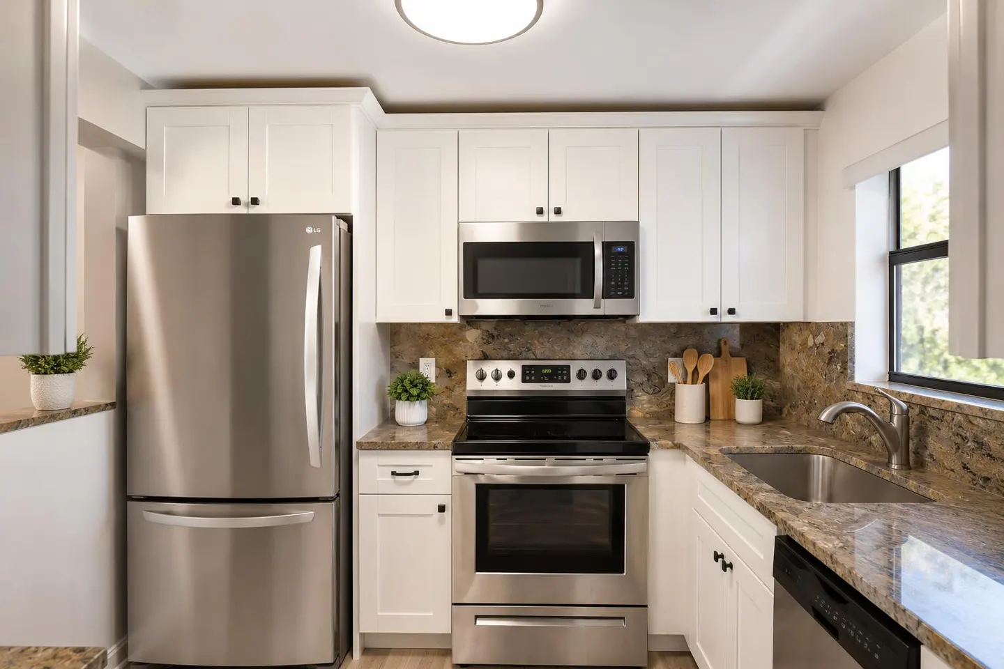 Bright kitchen with stainless steel appliances, white cabinets, and granite countertops. A window provides natural light.