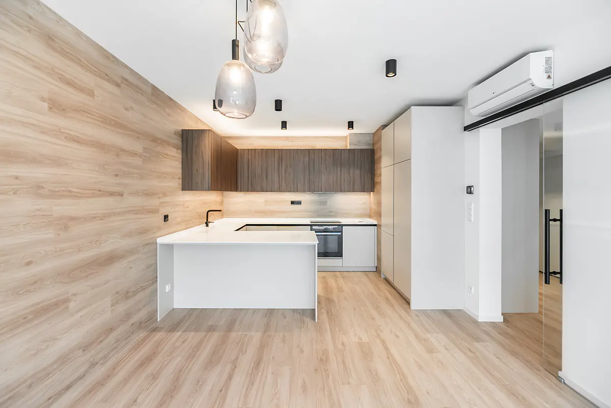 Modern kitchen with wood-paneled walls, white countertops, dark wood cabinets, and glass pendant lights.