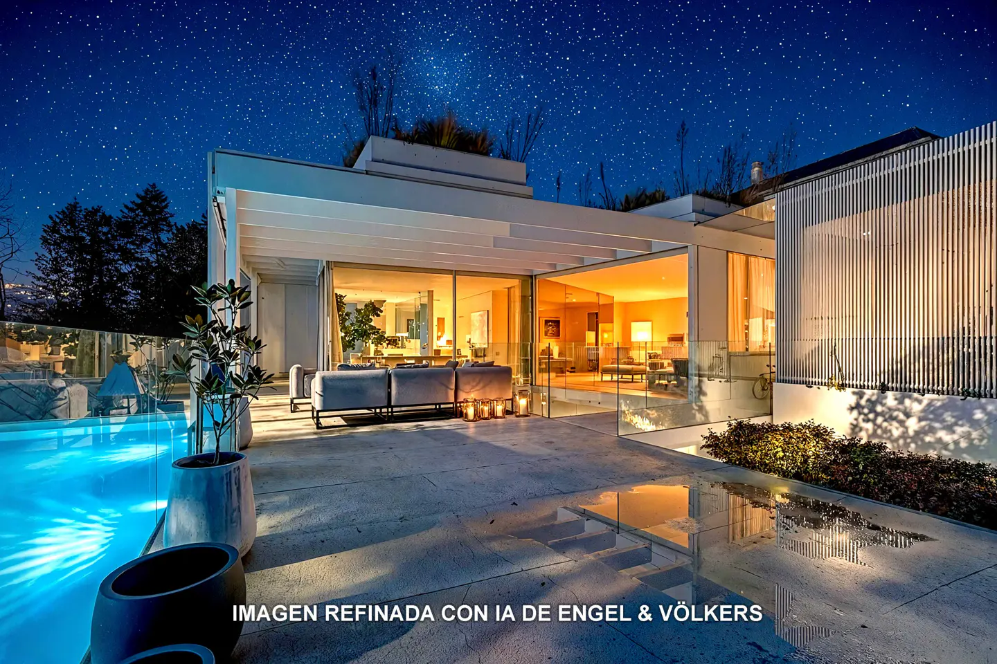 Modern home exterior at night with a pool, patio furniture, and starry sky. Interior lights glow through glass walls.