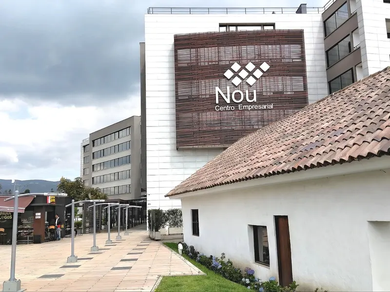 Exterior view of Nou Centro Empresarial, a modern white building with a brown tile roofed white building in front.