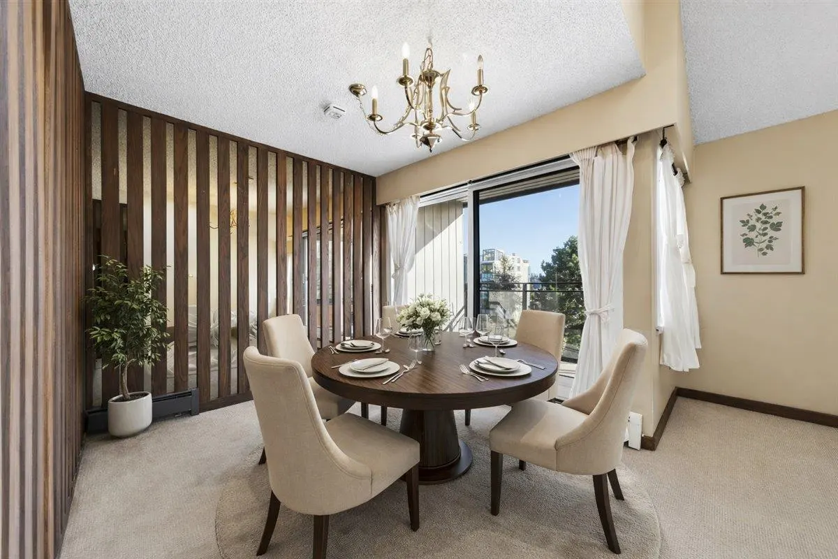 Dining room with a round wood table set for six, beige chairs, and a gold chandelier. Sliding glass doors lead to a balcony.