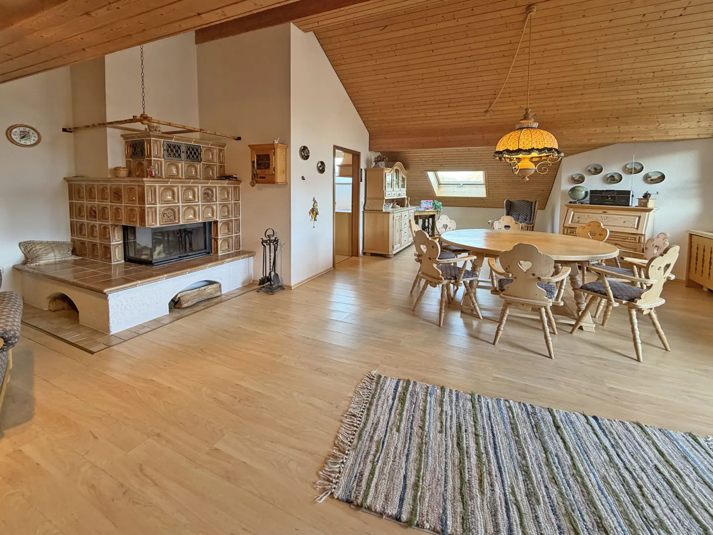 A bright, open living room with a tiled fireplace, wood floors, and a dining table with chairs.
