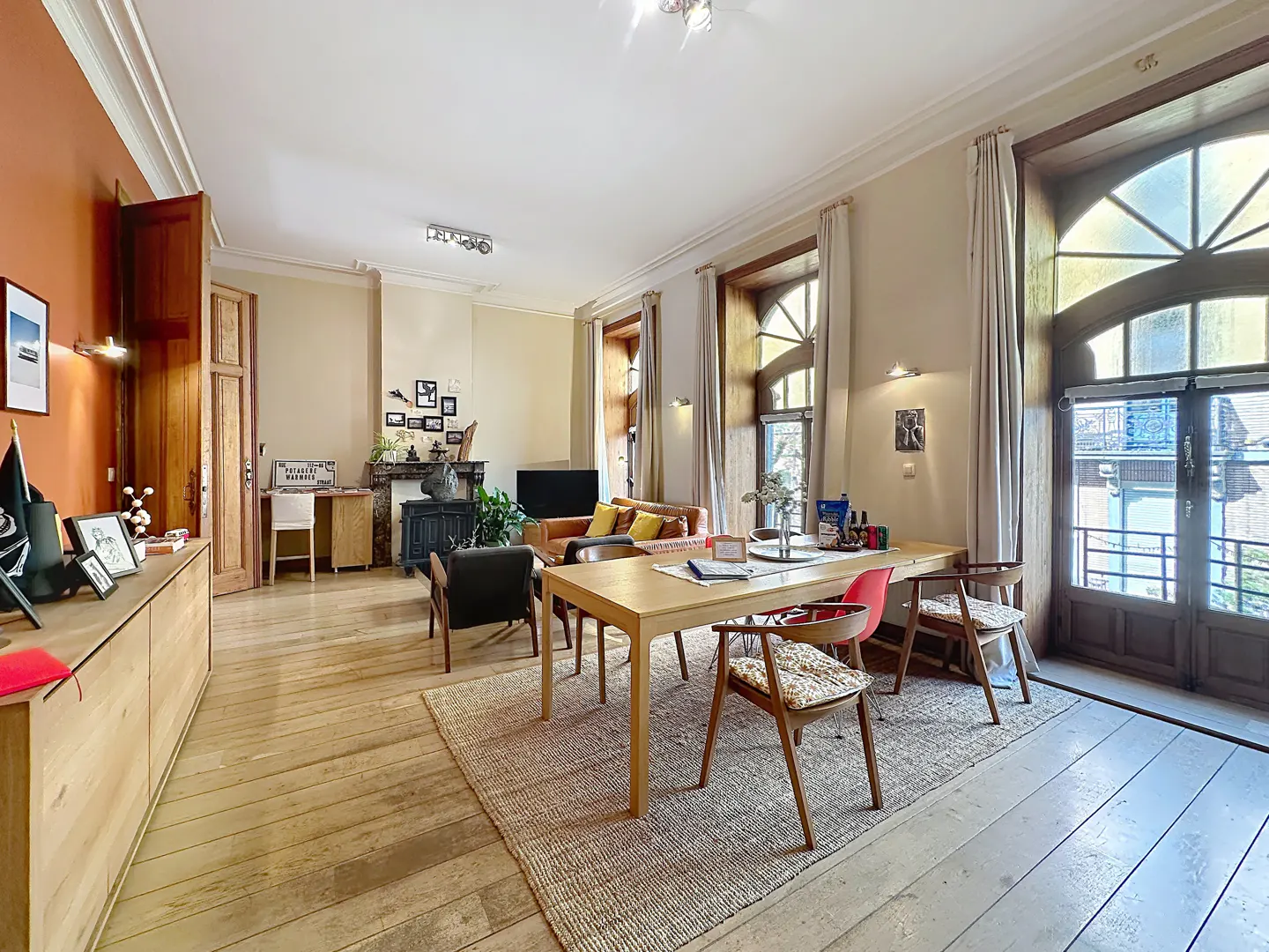 Bright, open living and dining area with hardwood floors, a large window, and a dining table with chairs.