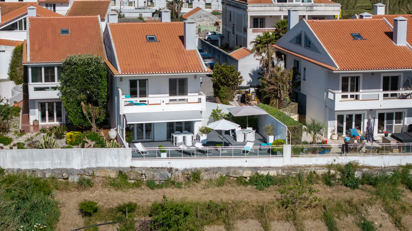 Aerial view of white houses with orange roofs, and outdoor seating areas with umbrellas.
